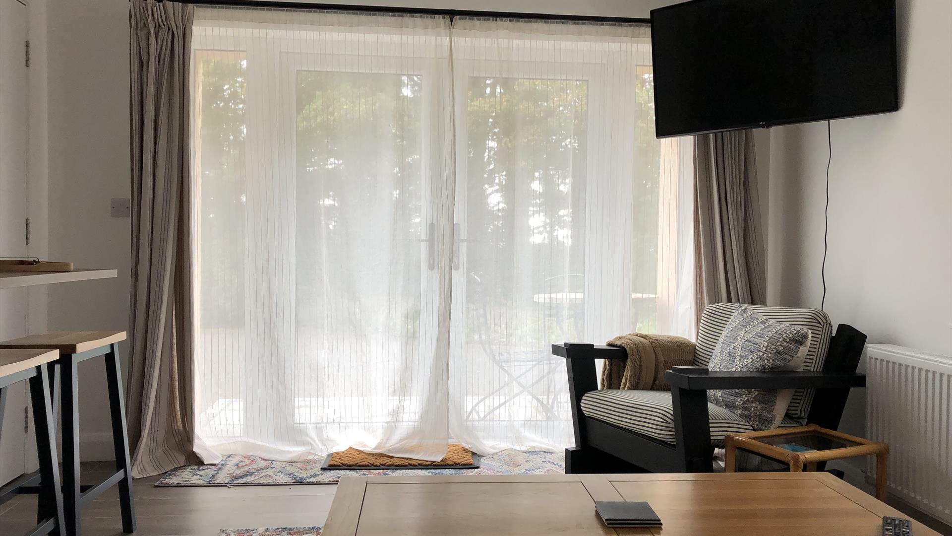Patio doors, TV, coffee table and chair in the living area  at The Heagry