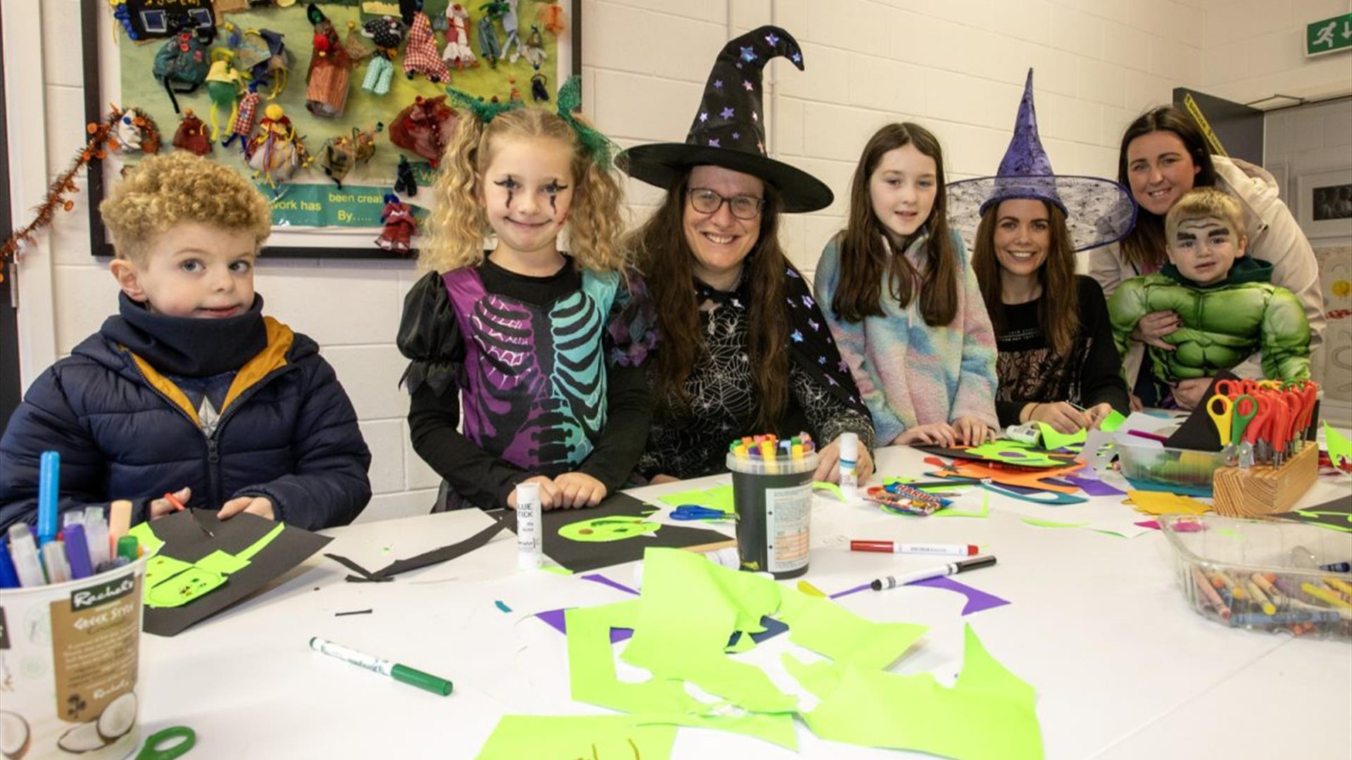 Image of children and faciltators in halloween fancy dress costumes crafting.