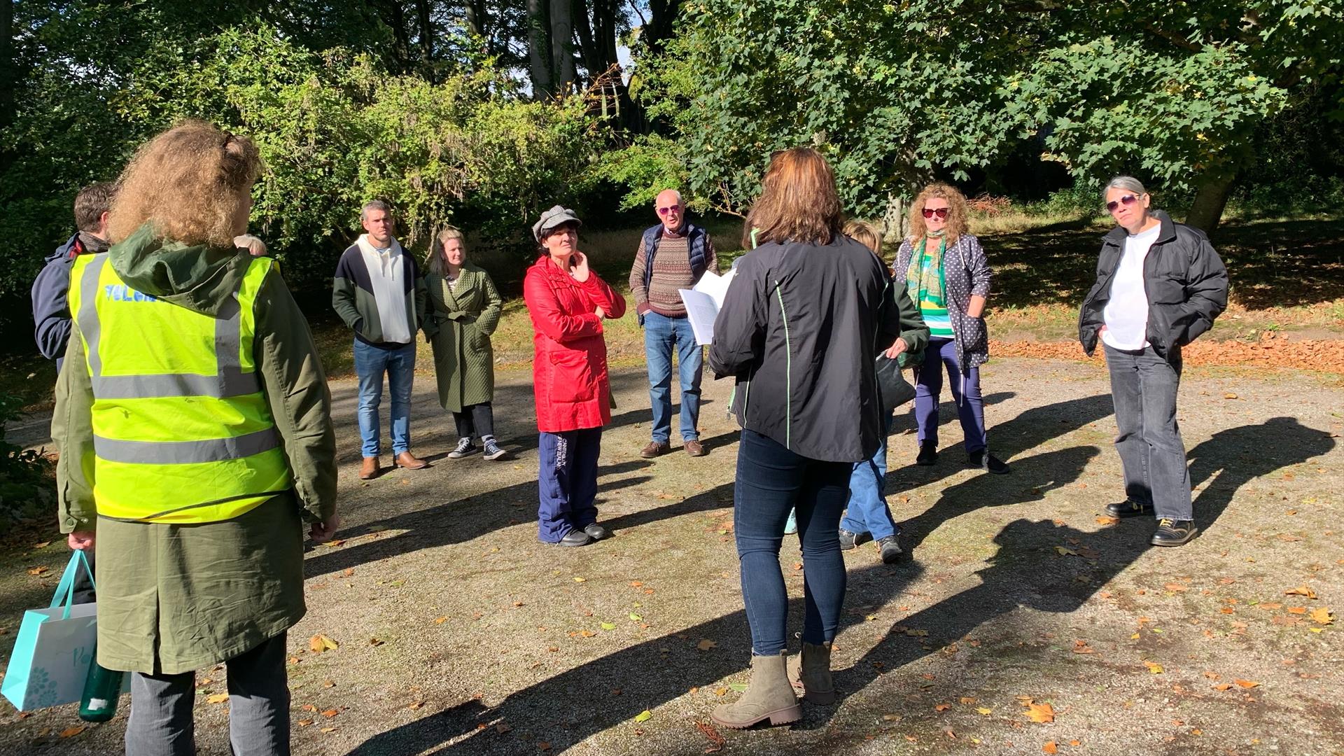 a group of people stand outdoors listening to a tour guide