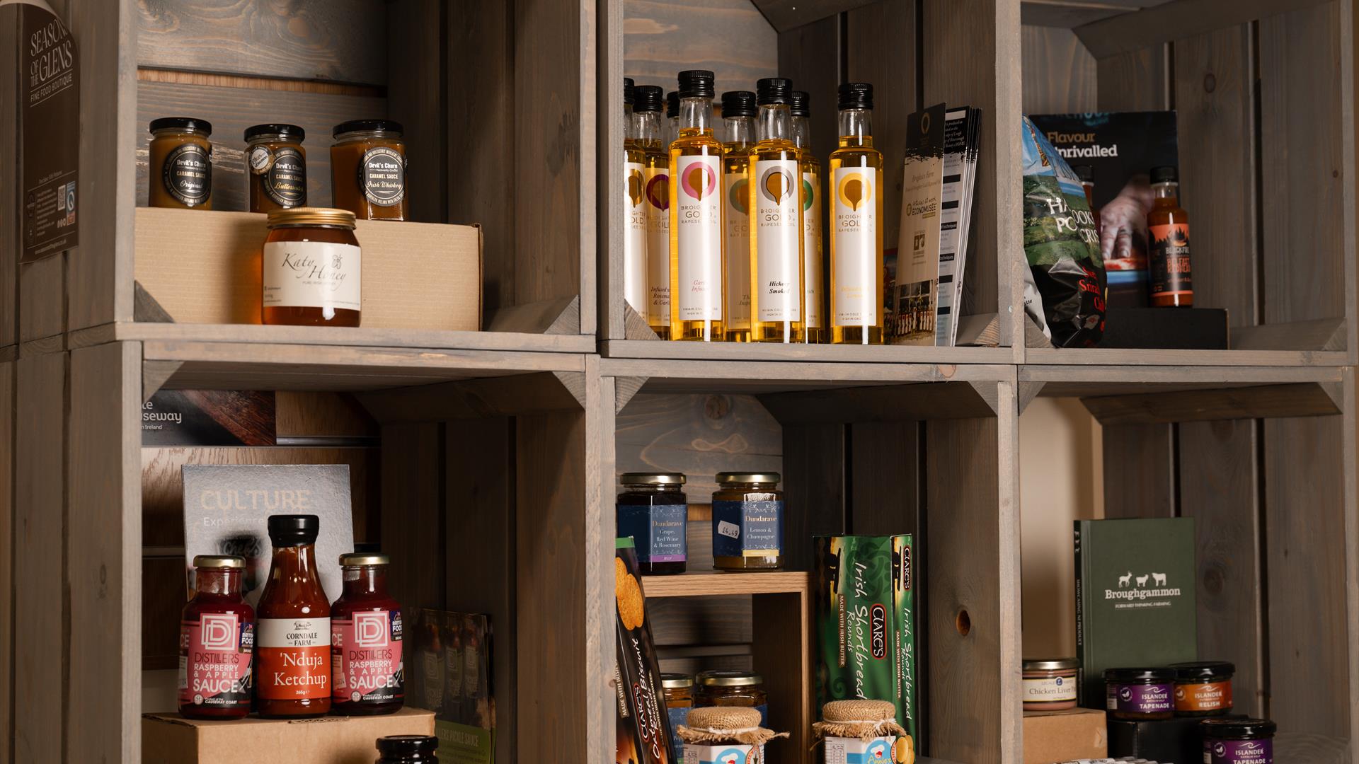 a selection of local produce from the Causeway Coast & Glens including oils and preserves are displayed inside wooden crates