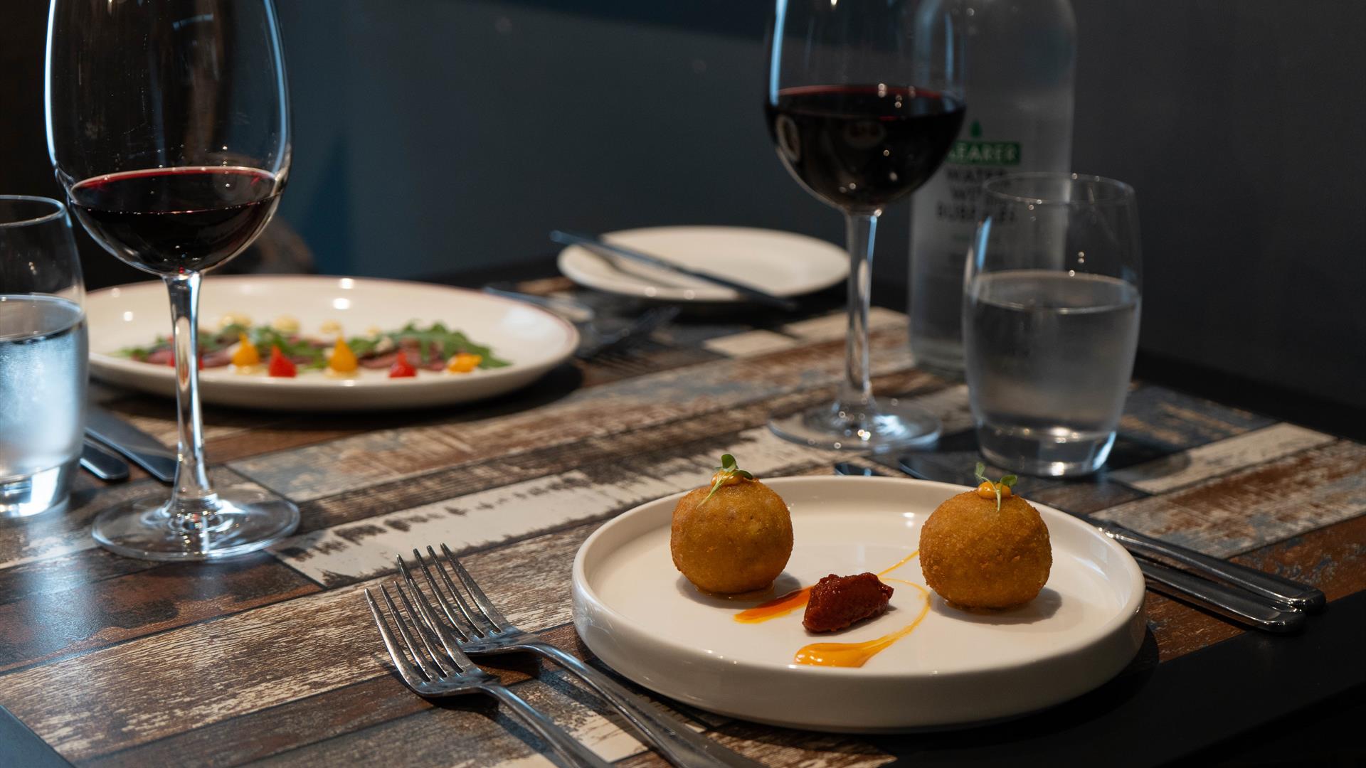 Italian dishes and red wine sit on a restaurant table