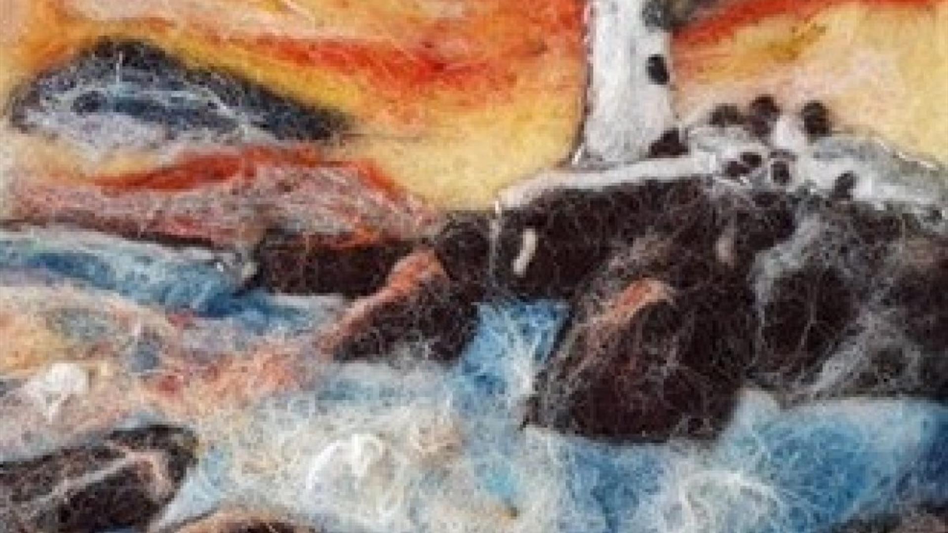 a felted landscape depicting a lighthouse on the rocks with an orange sky