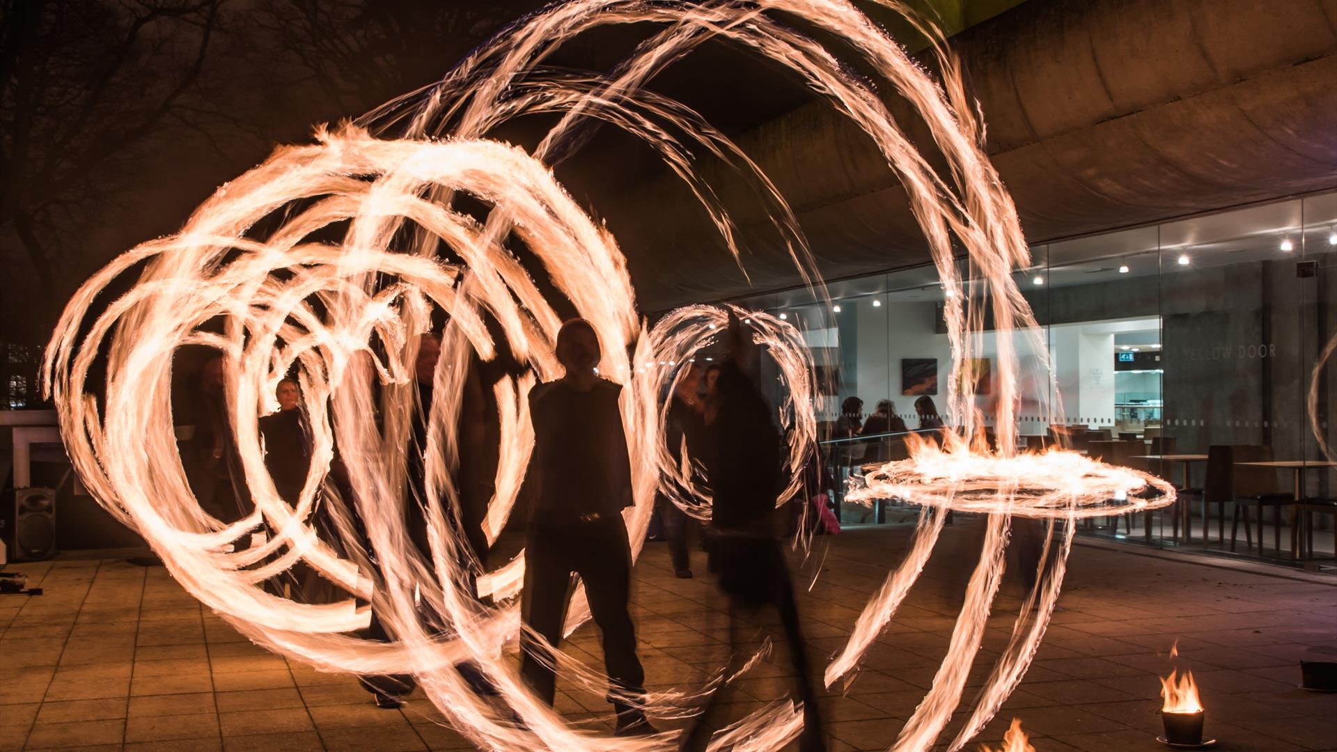 people spinning wheels of fire in the darkness outside flowerfield