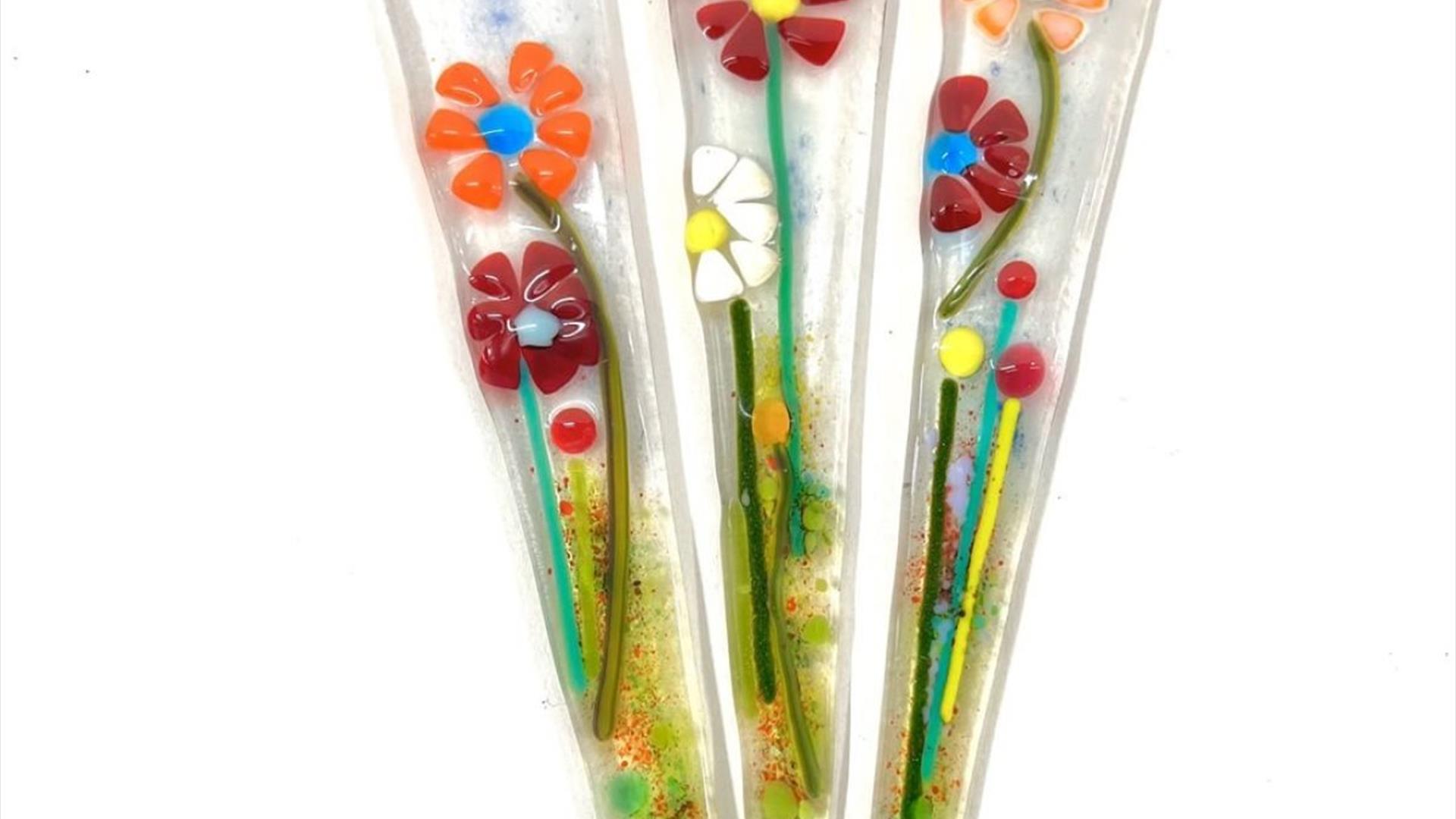 fused glass stakes with colourful flowers on them