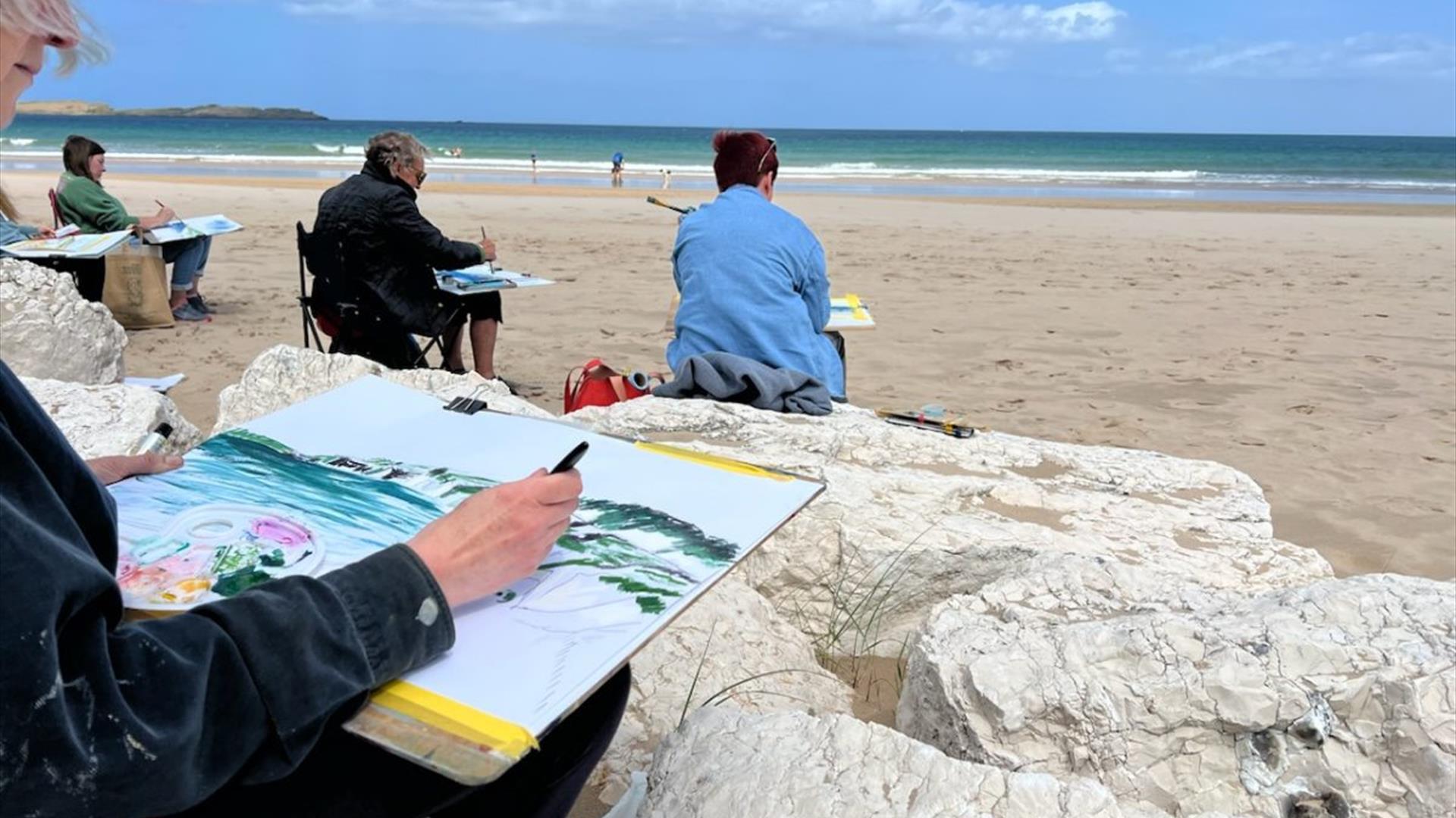people painting pictures on a beach