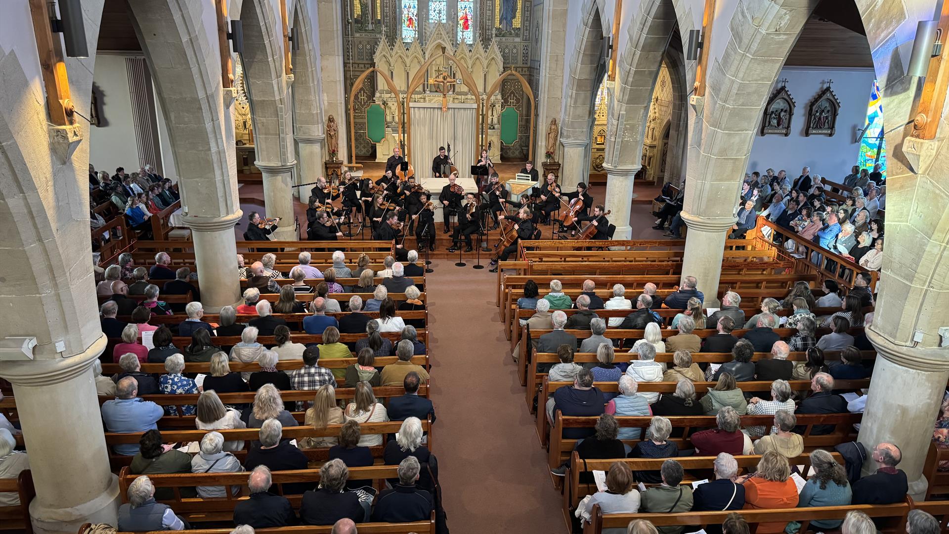 The ulster orchestra performs in the hall of St. Patrick's and St. Brigid's church.