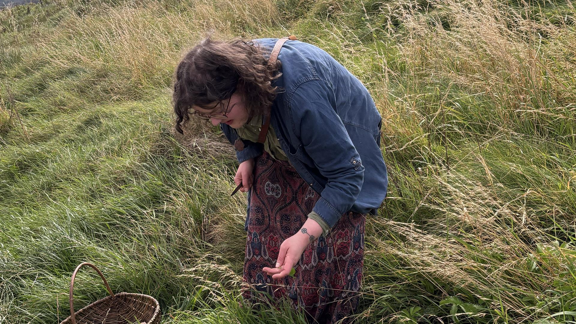 a woman stands in a field, picking weeds