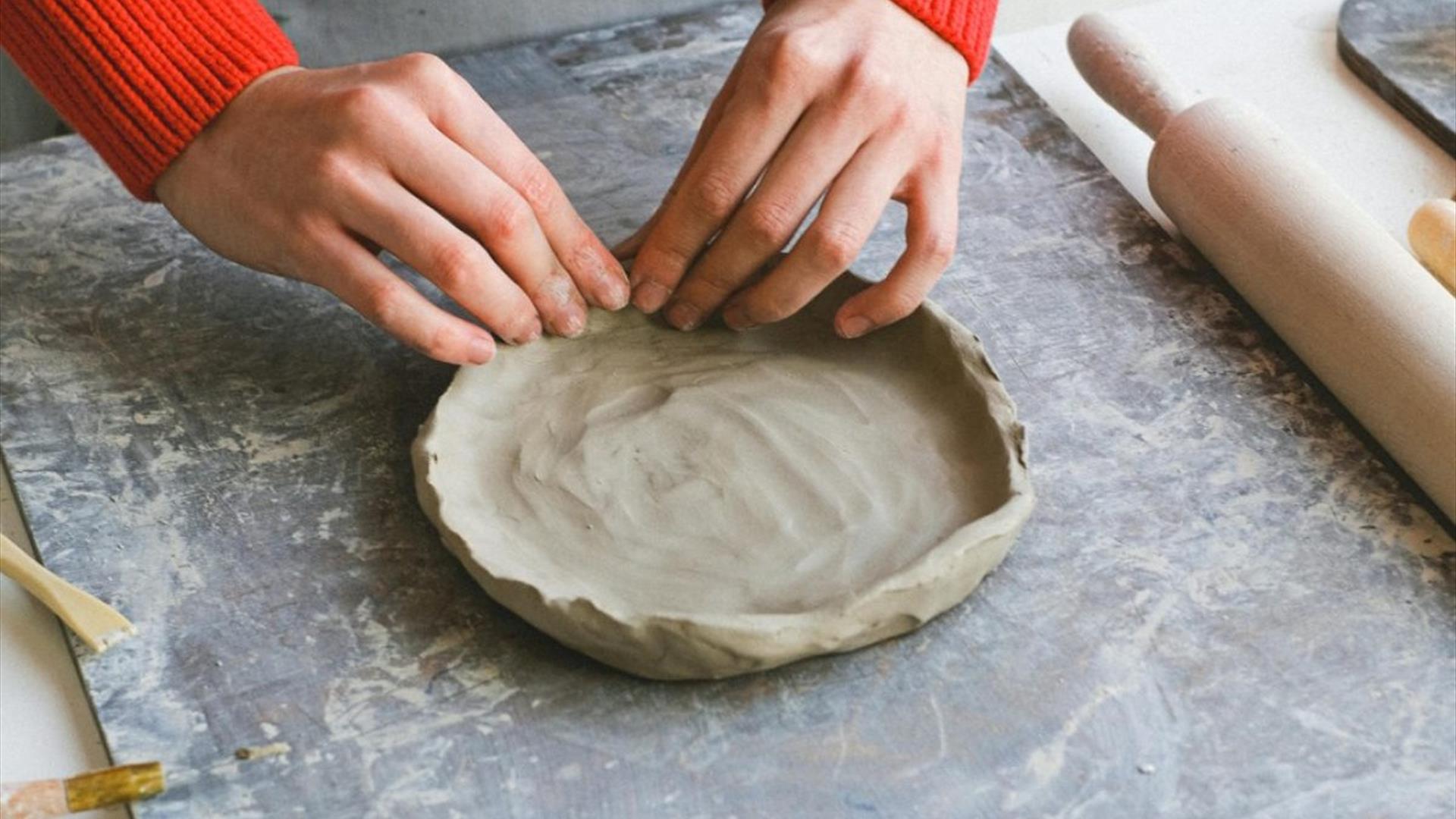 a person working on a shallow clay dish