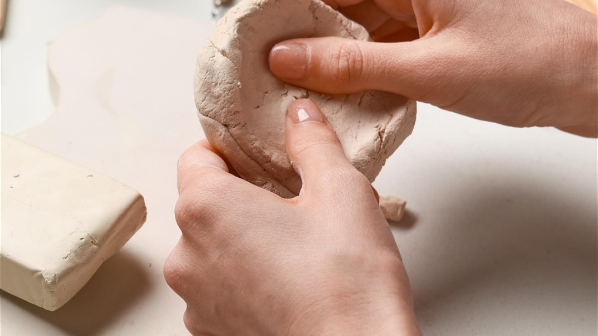 a pair of hands sculpting a piece of ceramic clay