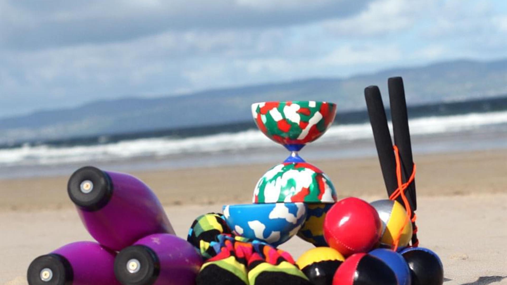 juggling props sit on a beach with the ocean in the background