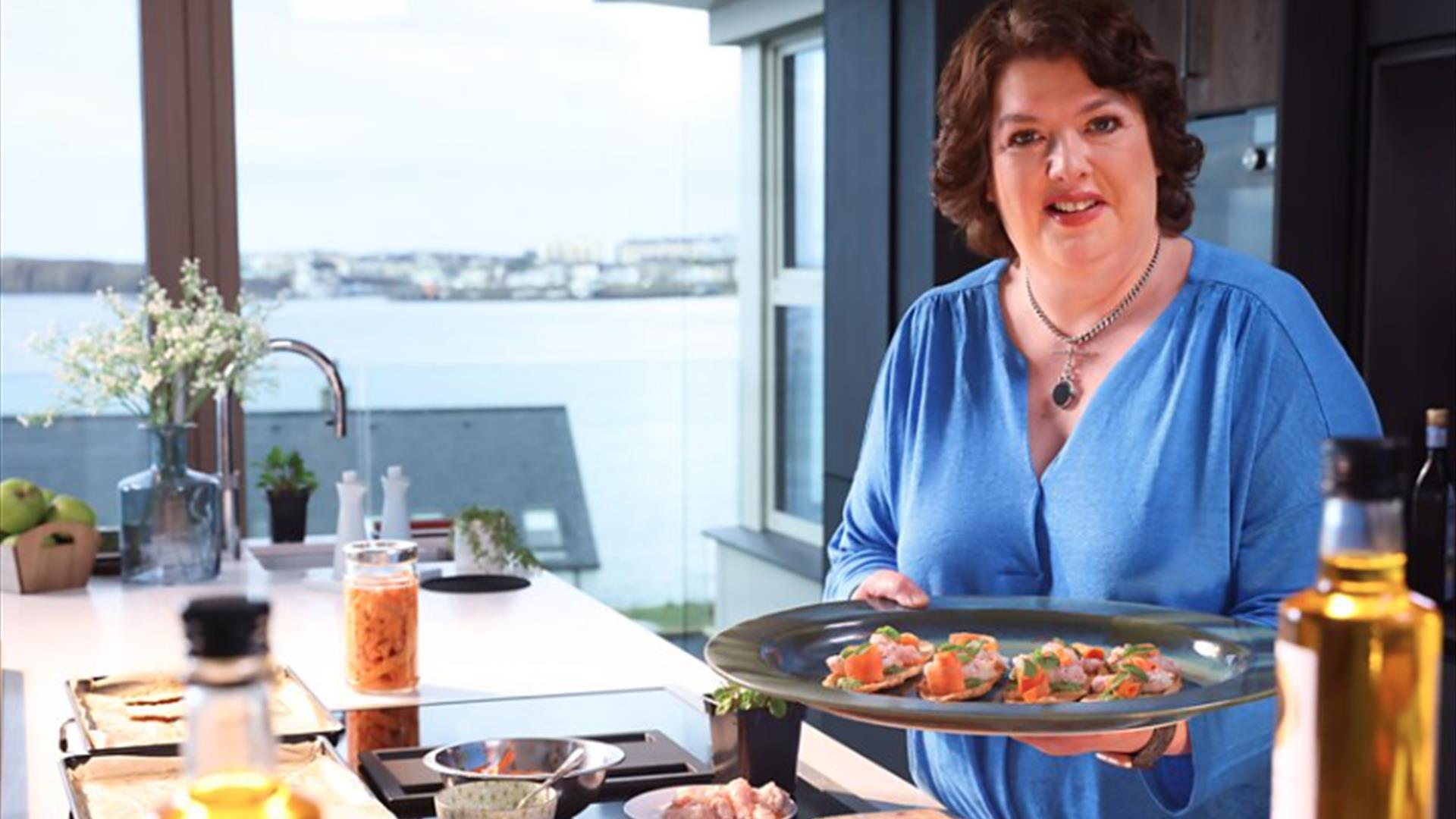 Paula McIntyre stands with plate of canapes in a kitchen