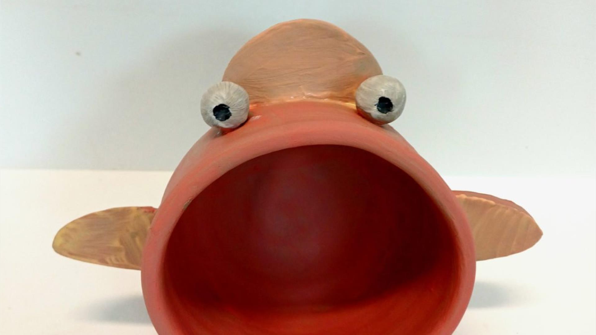 a clay fish with a wide mouth for holding speakers