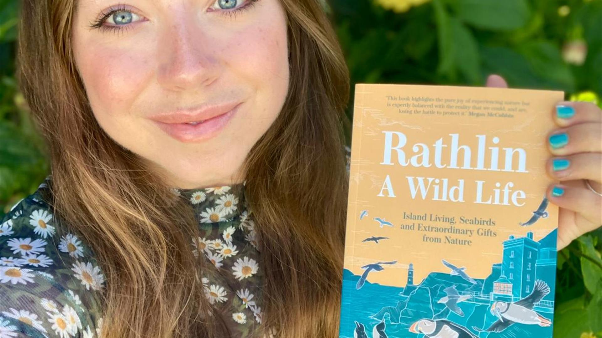 Ruby Free holding up her book, "Rathlin Wildlife" for the camera.