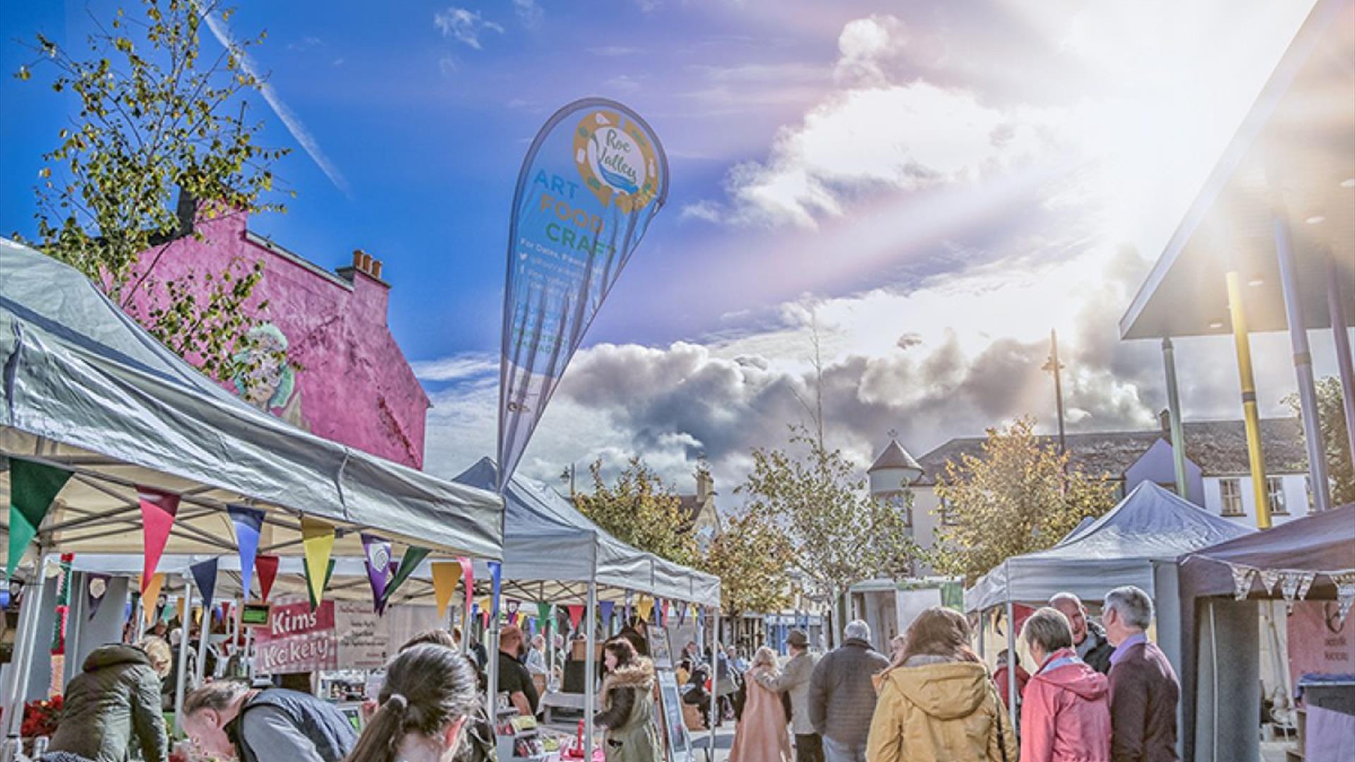 A sunny blue sky looks down on the top of white tent stalls and smiling crowds at the Roe Valley.