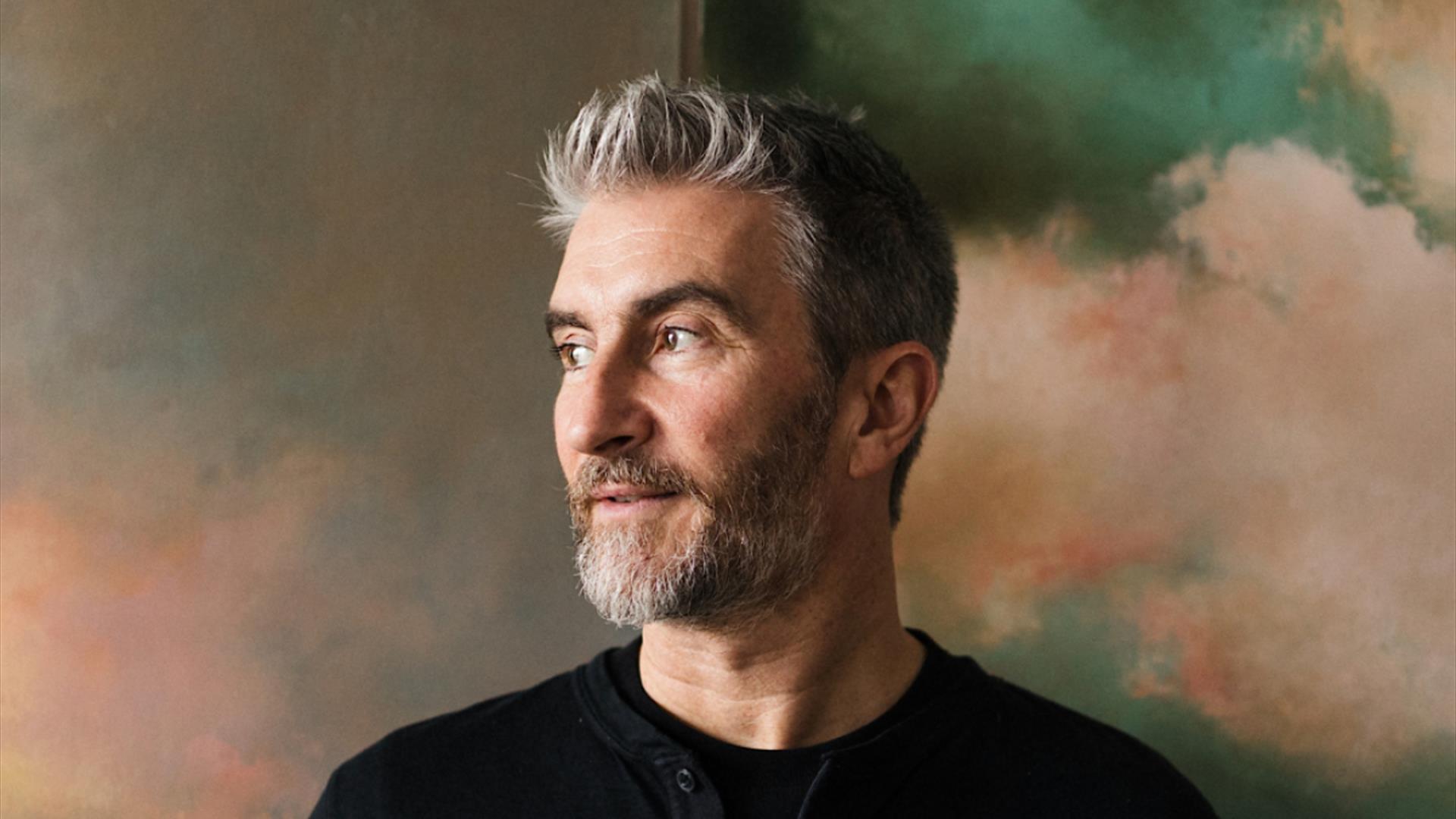 stuart quigley standing in front of two of his artworks