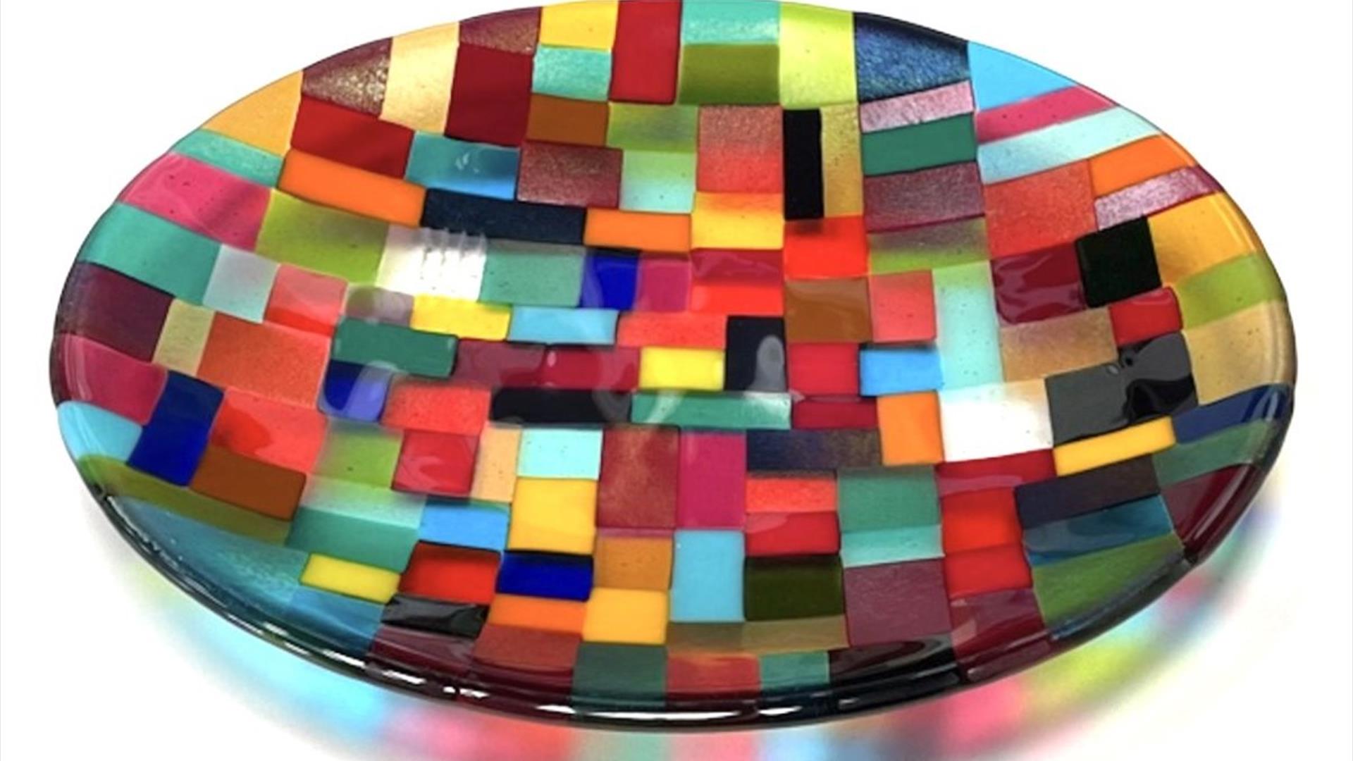 A shallow glass dish made from various different colours arranged in geometric patterns.