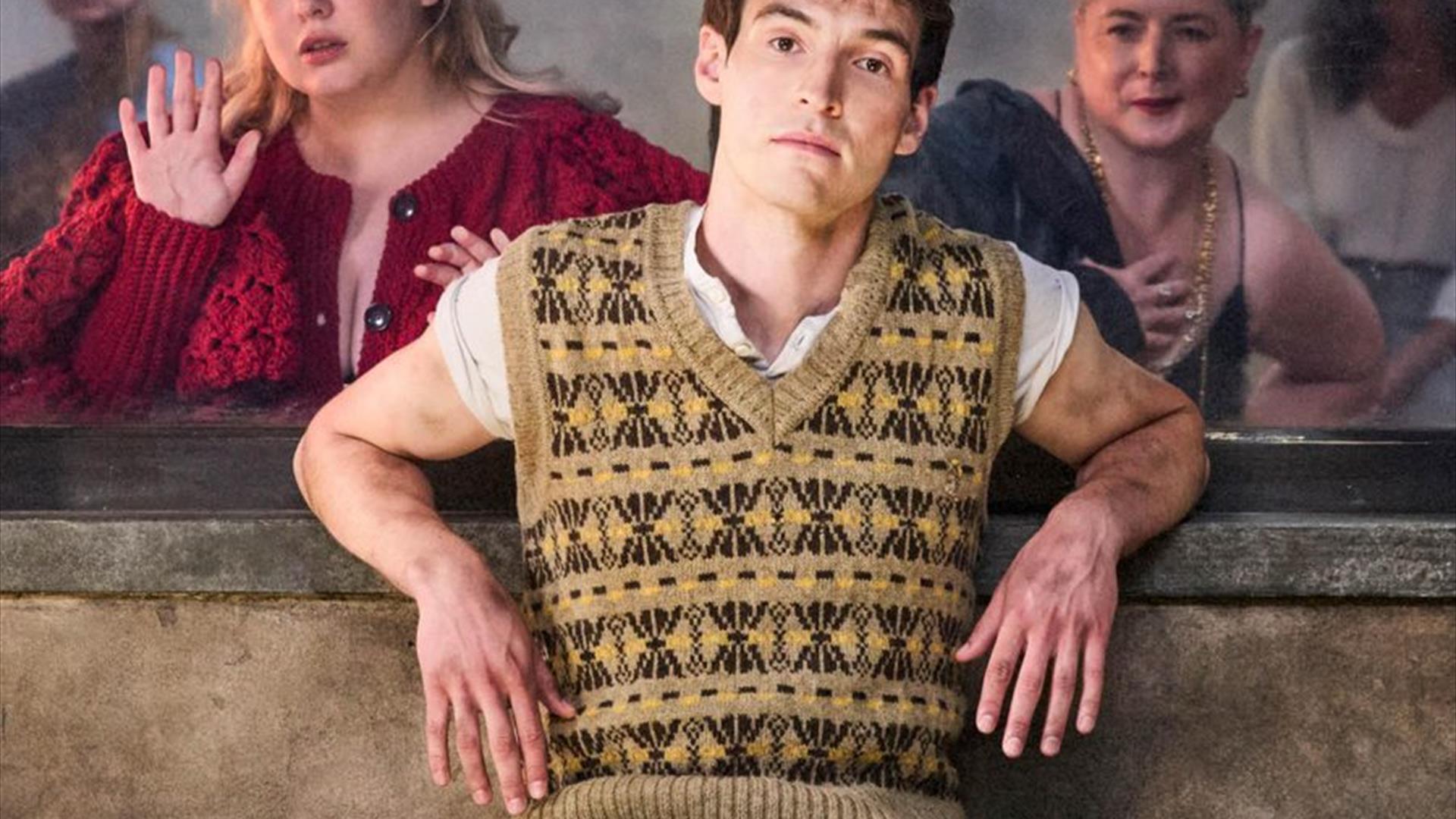 central characters of the play lined up behind a window all looking at the protagonist