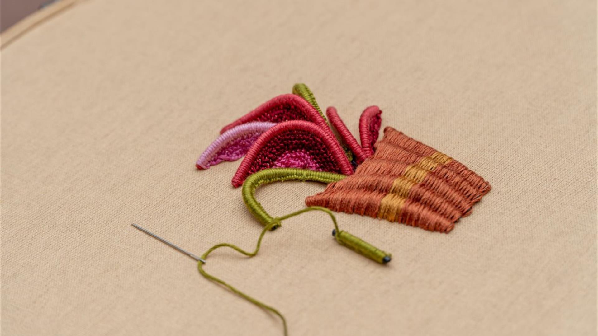 close up of a stumpwork embroidery piece with a needle stuck int he embroidery hoop canvas