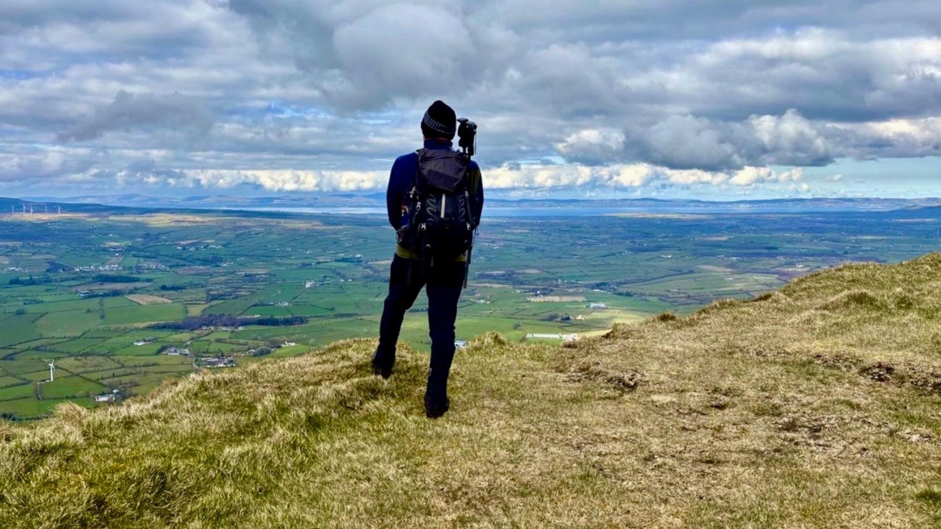 A hiker stands atop a mountain admiring the view