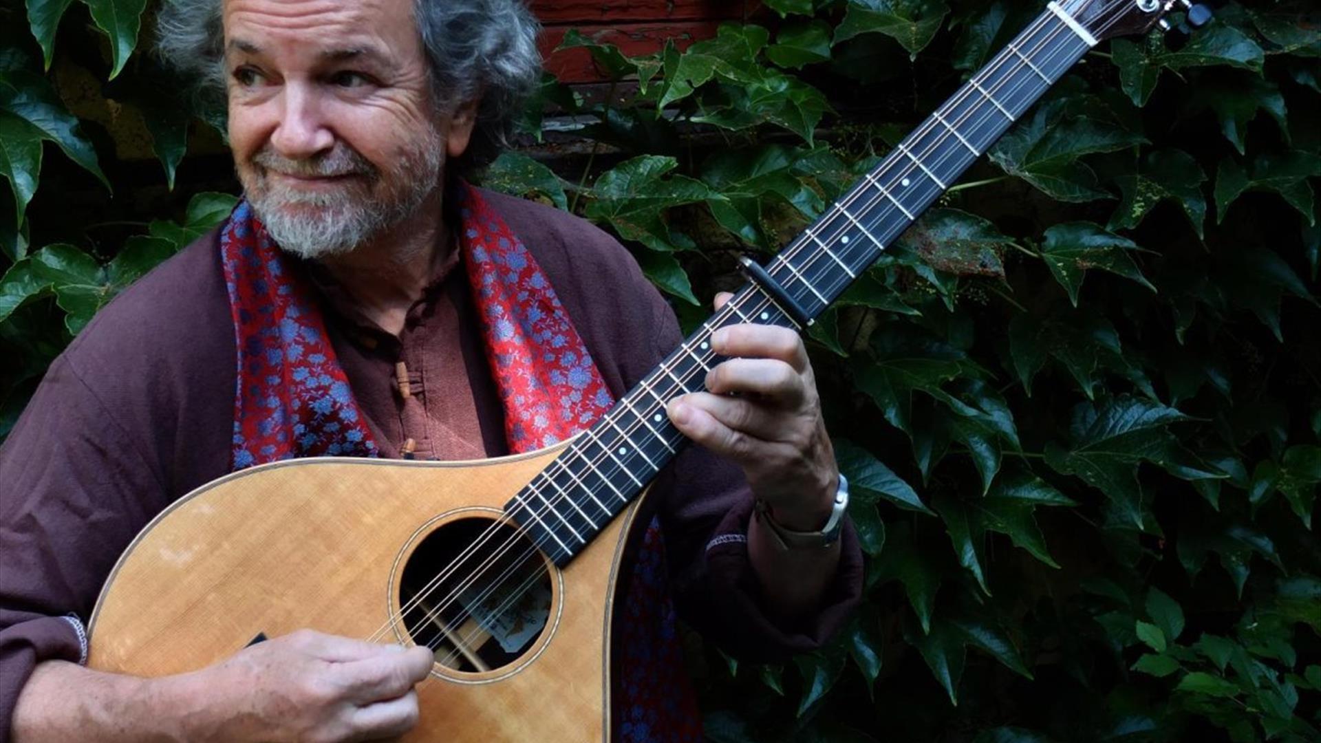 Image of Andy Irvine holding a lute outside.