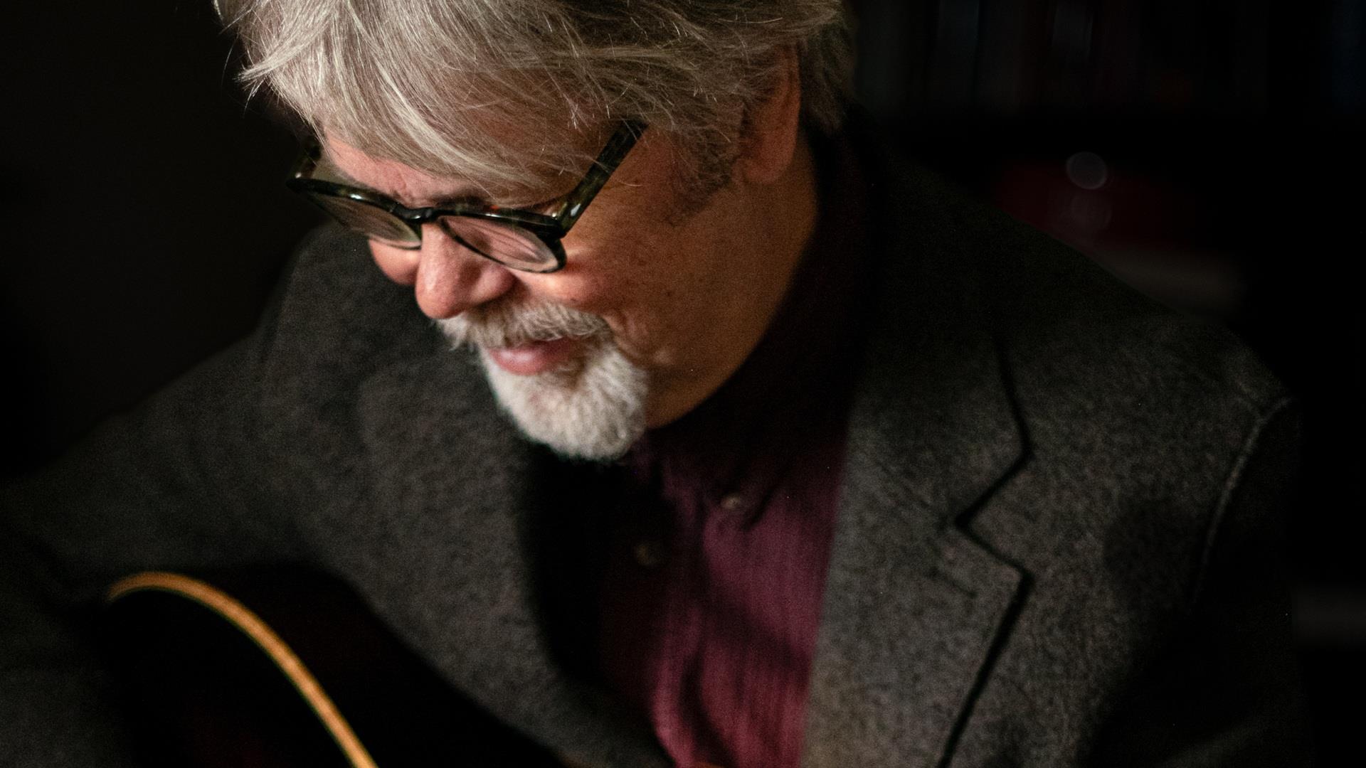 musician Anthony Toner looks down towards an acoustic guitar