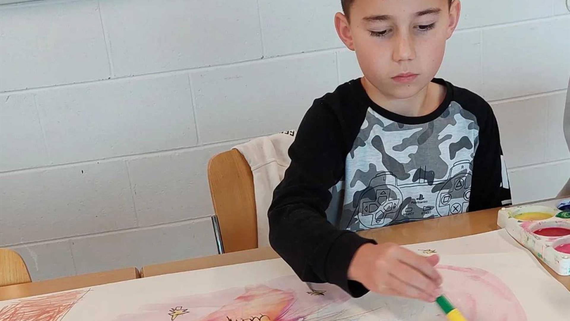 a child painting with a large paint brush.