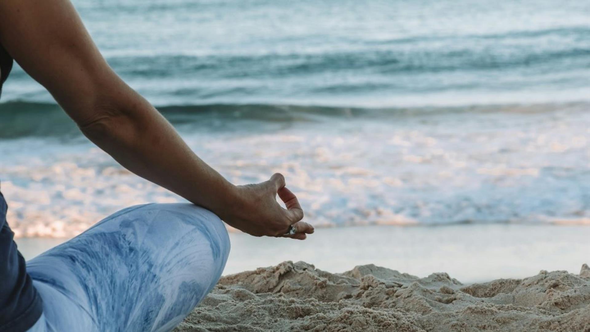 A person sitting in a relaxing pose at a beach with an ocean view