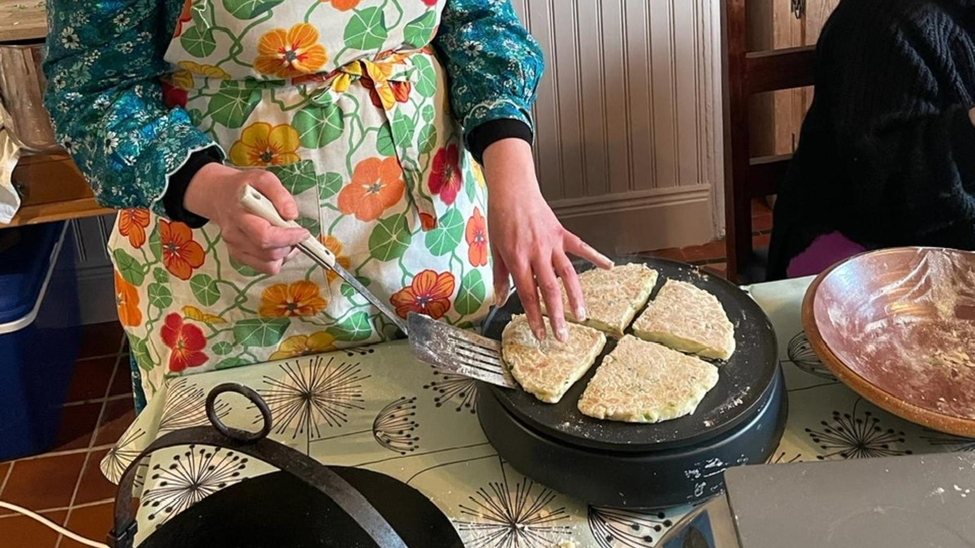 person in a apron bakes bread on a griddle pan