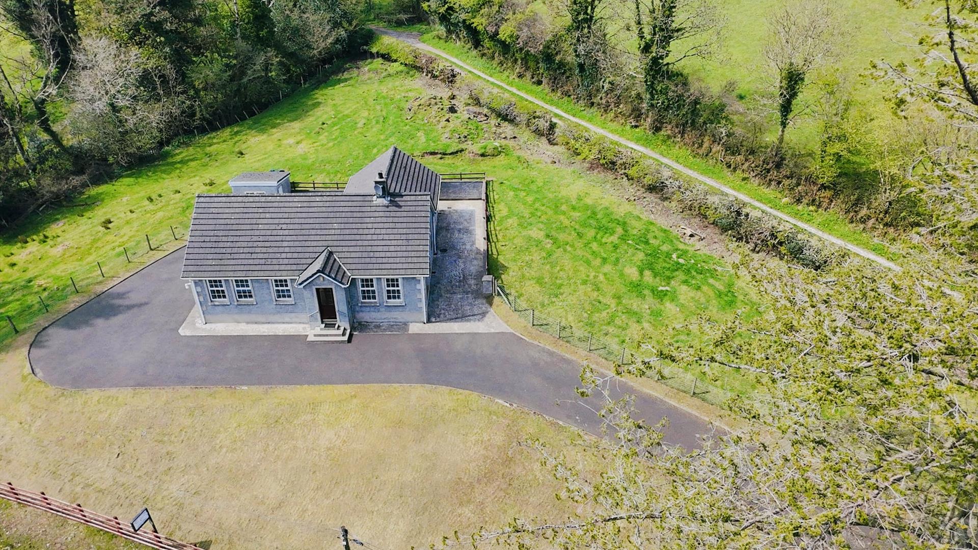 Aerial view with green woodland, with tall trees surrounding the property in a rural countryside setting.