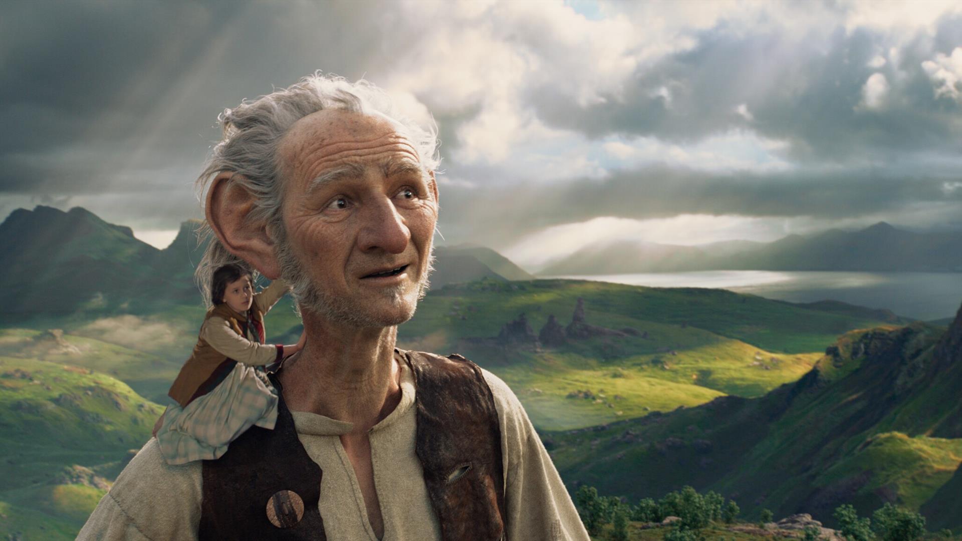 The BFG stands with a small child on his shoulder, with the countryside in the background.