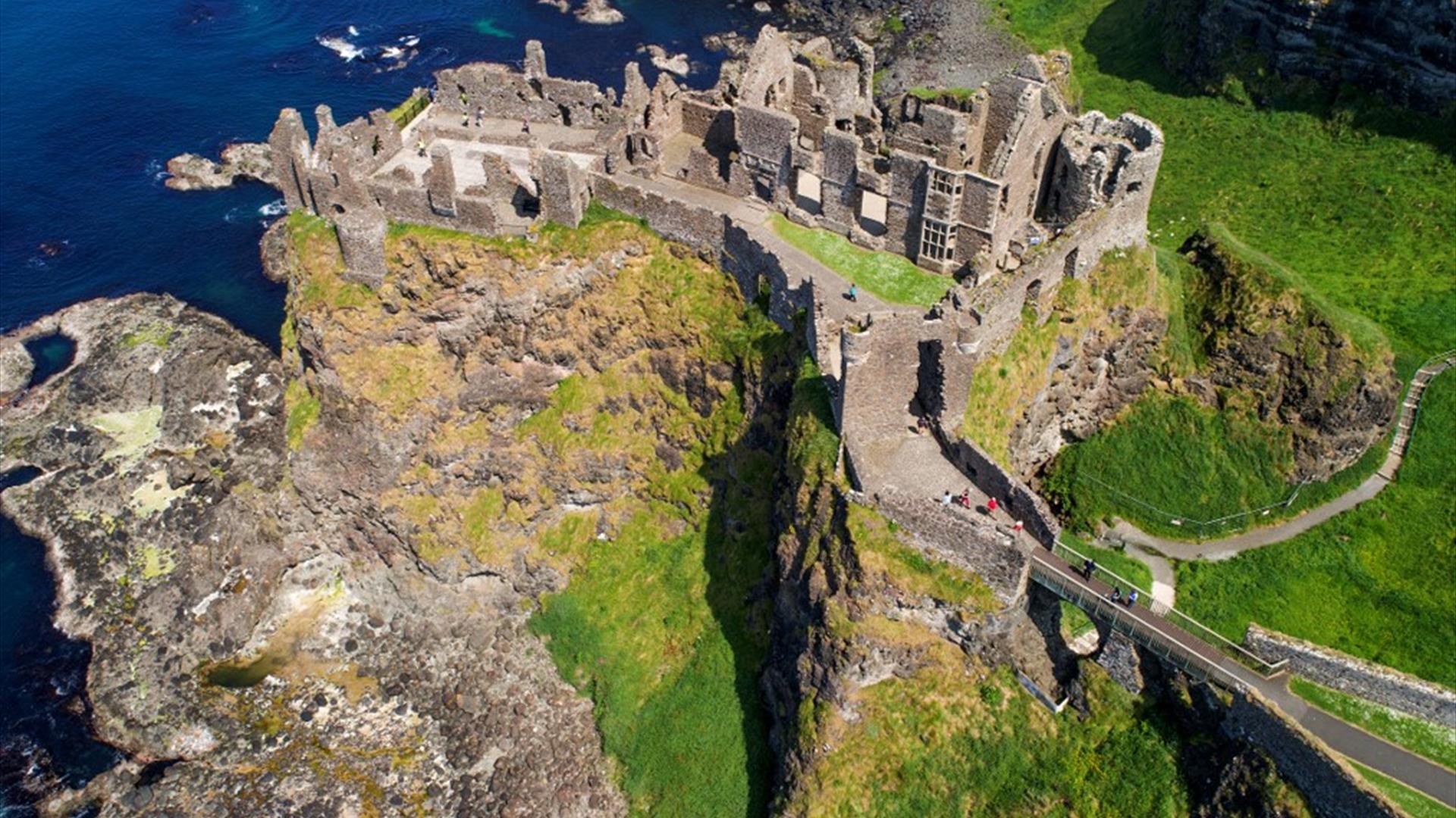 The ruins of Dunluce Castle perched on the edge of a cliff with the sea below