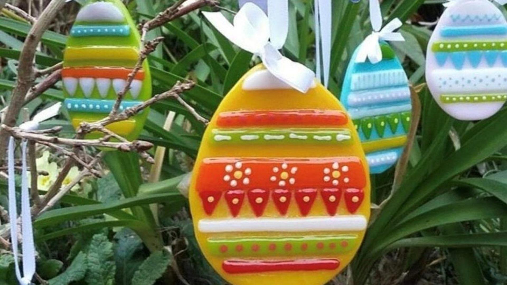glass easter eggs  layered with coloured glass shapes and powders hanging on a plant