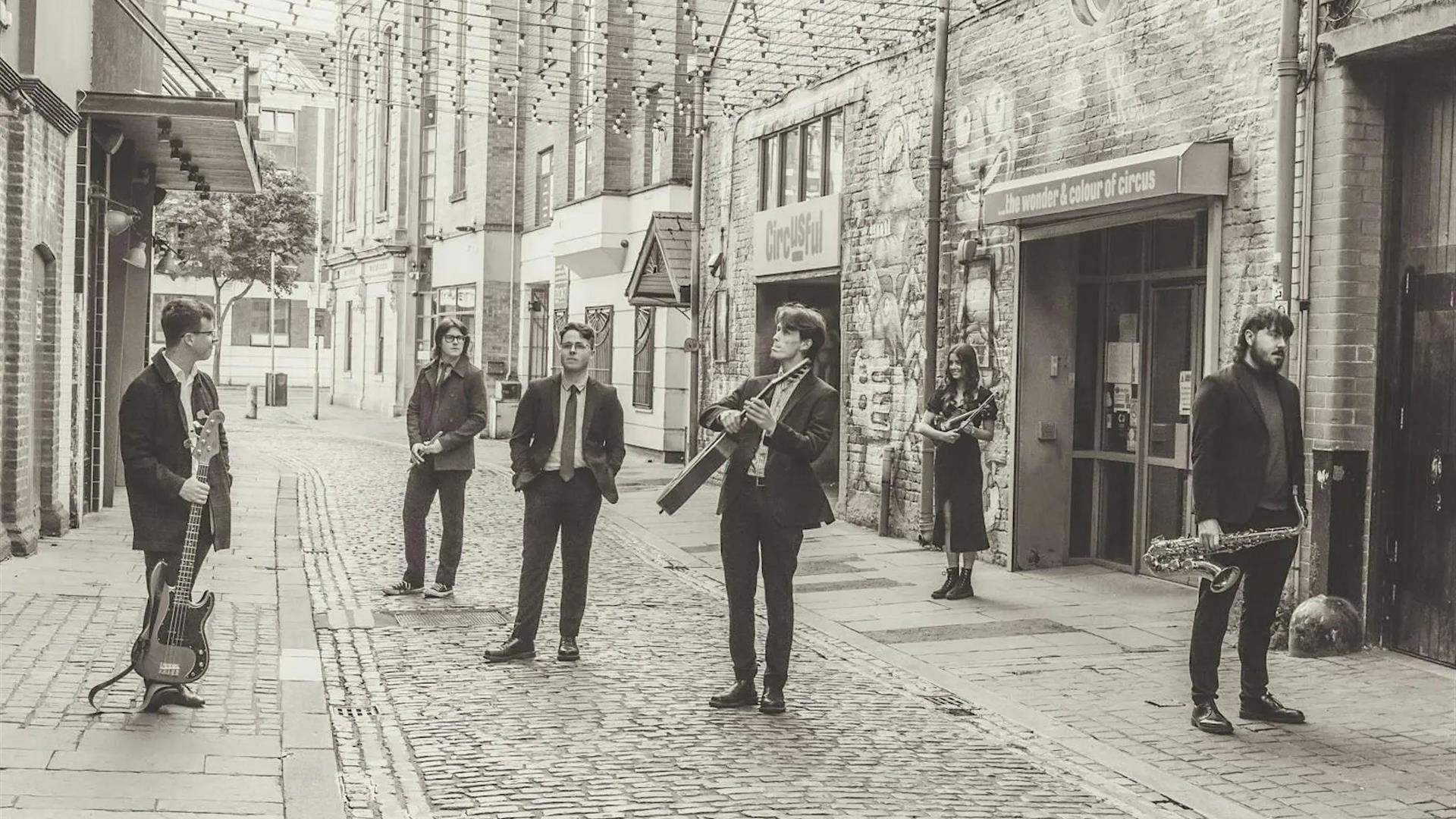 the band members of polar bolero standing on an empty street in black and white
