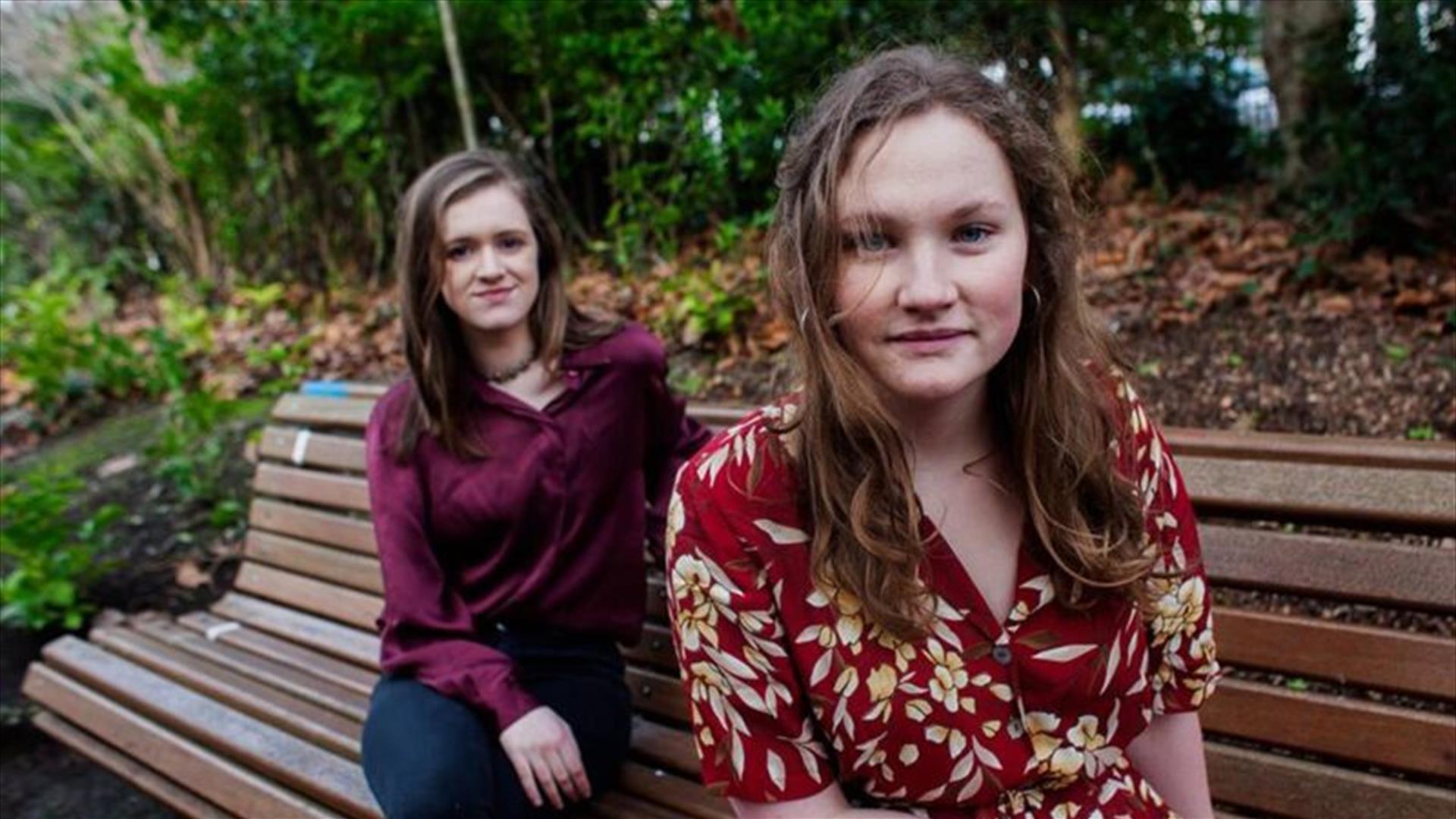 Laura Quirke and Claire Kinsella of the band Lemoncello sitting on a bench together