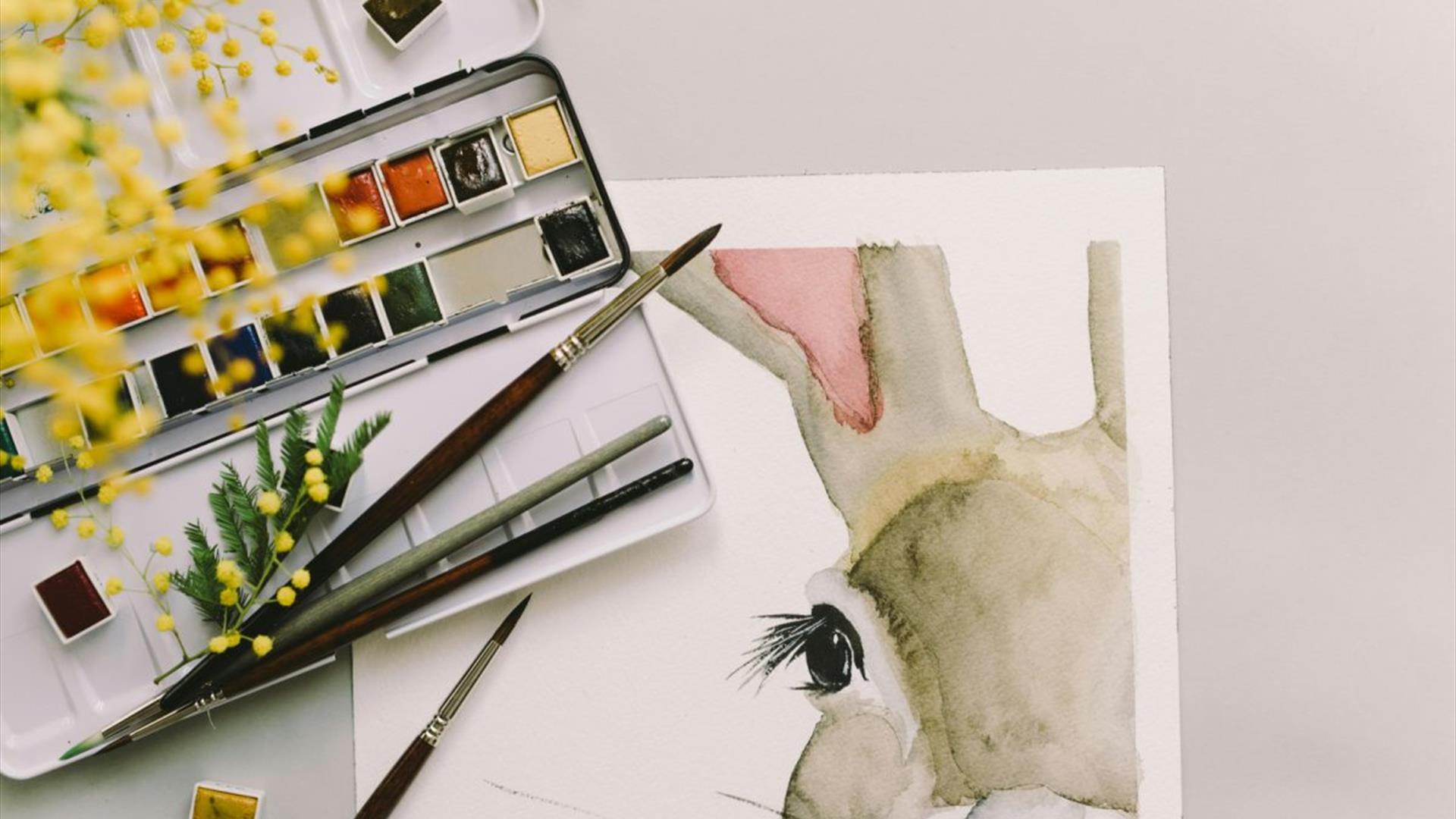watercolour rabbit painting accompanied by brushes and a palette