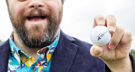 James Martin MBE, holding a golf ball and smiling for the camera.