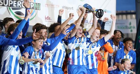a male youth football team celebrates winning a trophy