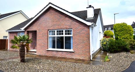 Exterior front and side view of Beachside Bungalow with gravelled drive and garden.