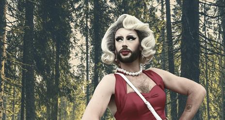 Drag Queen Cherrie On Top pictured against a forest backdrop