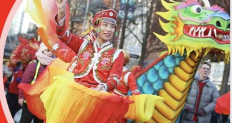 Image shows a lady in traditional Chinese dress with fans and a parade dragon