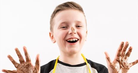 boy with hands covered in melted chocolate
