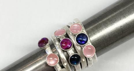 A number of silver rings all stacked together, encrusted with a number of semi precious stones ranging.