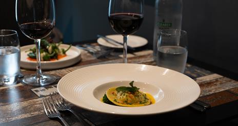 Italian food in dishes and red wine sit on a table in a restaurant