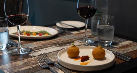 Italian dishes and red wine sit on a restaurant table