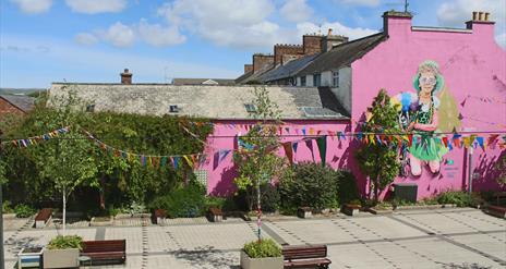 Image of Drumceatt  in the sunshine with bunting hanging across the square.
