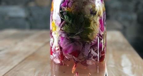 Jar filled with naturally infused gin, containing  beautiful, colourful ingredients