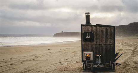 sauna standing on a beach backed by cliffs