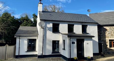 Photo of front of cottage showing position next to the attached old mill