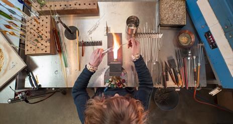 aerial view of a woman working with glass over a flame