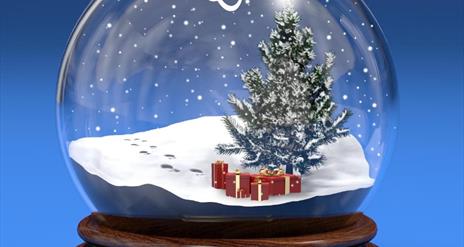 a festive snow globe with a tree and presents inside.